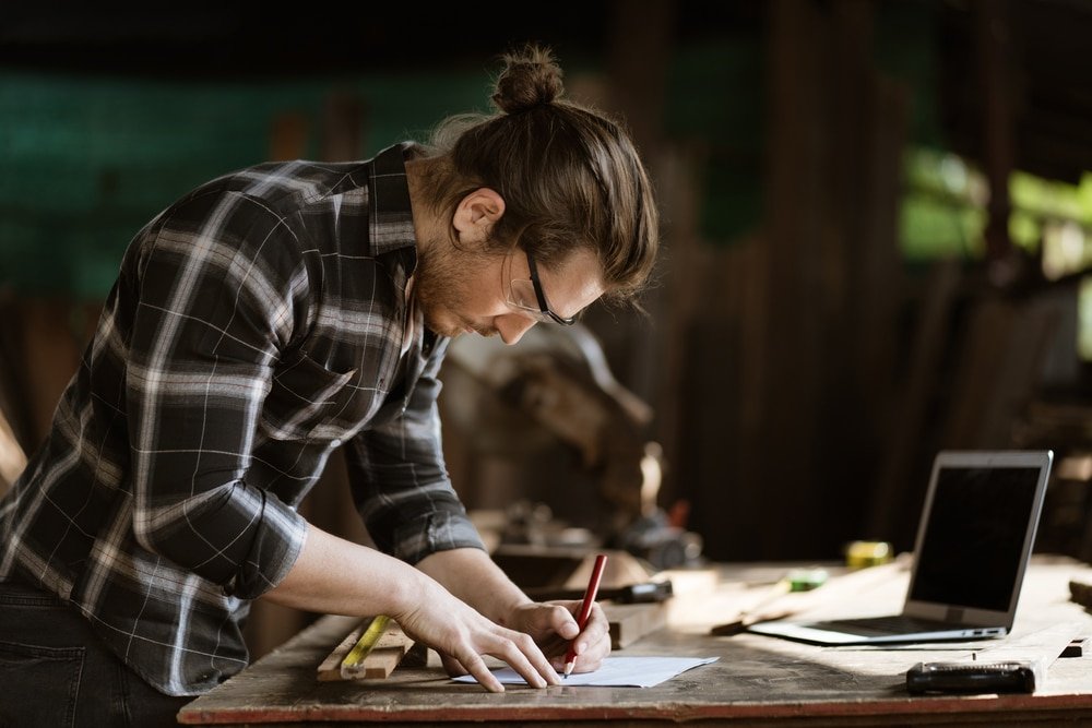 Young,Hipster,Carpenter,Man,Working,With,Computer,Laptop,In,Workshop